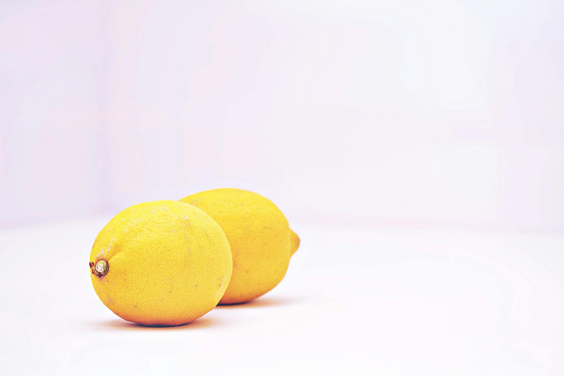 Two vibrant lemons on a white background symbolizing sensory stimulation and pleasure