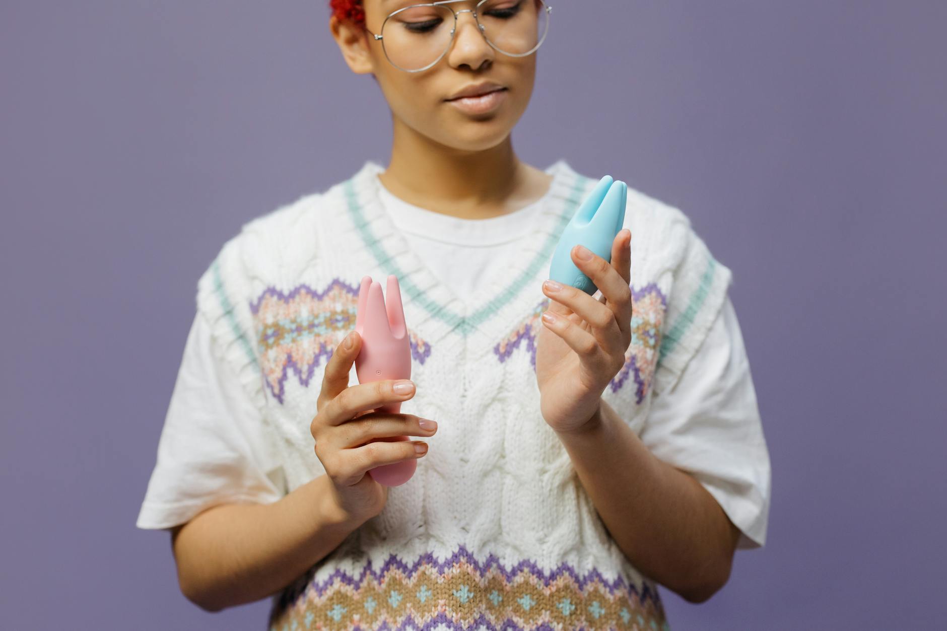 Woman holding a blue clitoral vibrator, contemplative expression