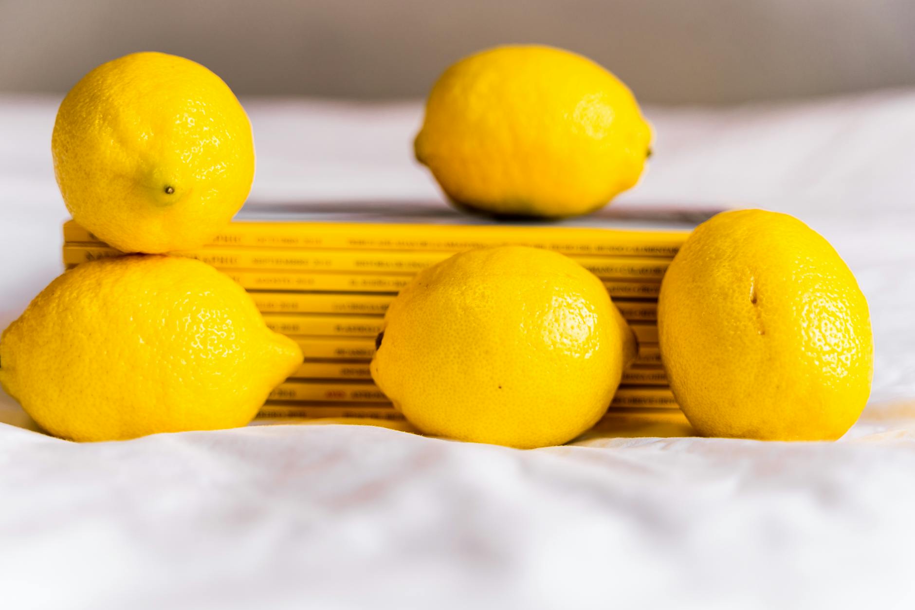 Yellow lemons stacked with books on white fabric, symbolizing fresh perspective after stress